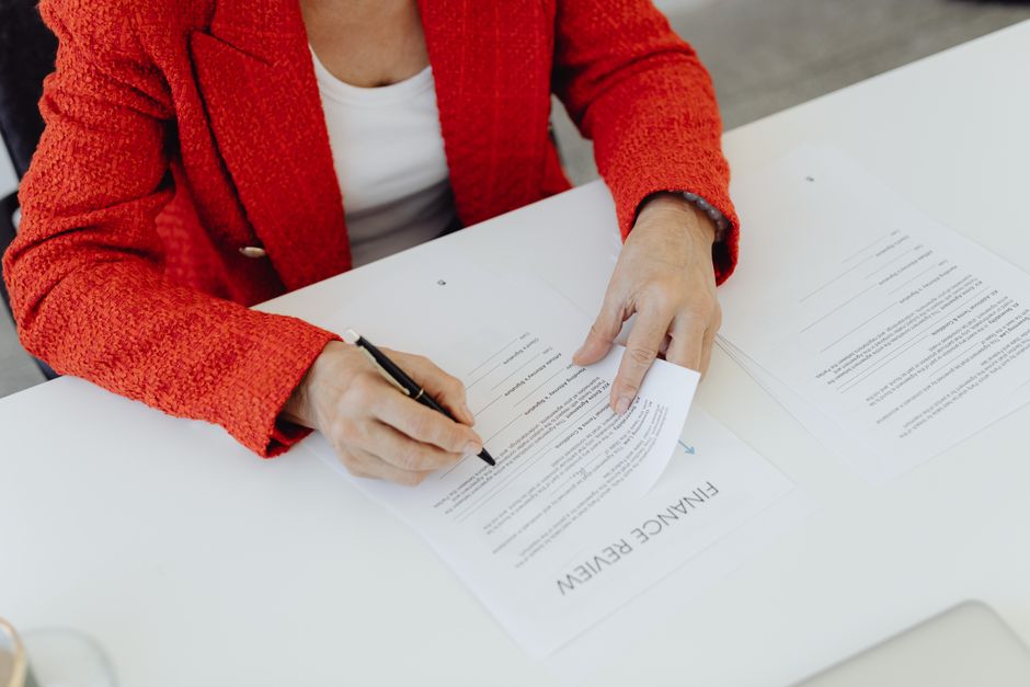 Una persona revisa y firma un documento financiero antes de darlo por bueno.